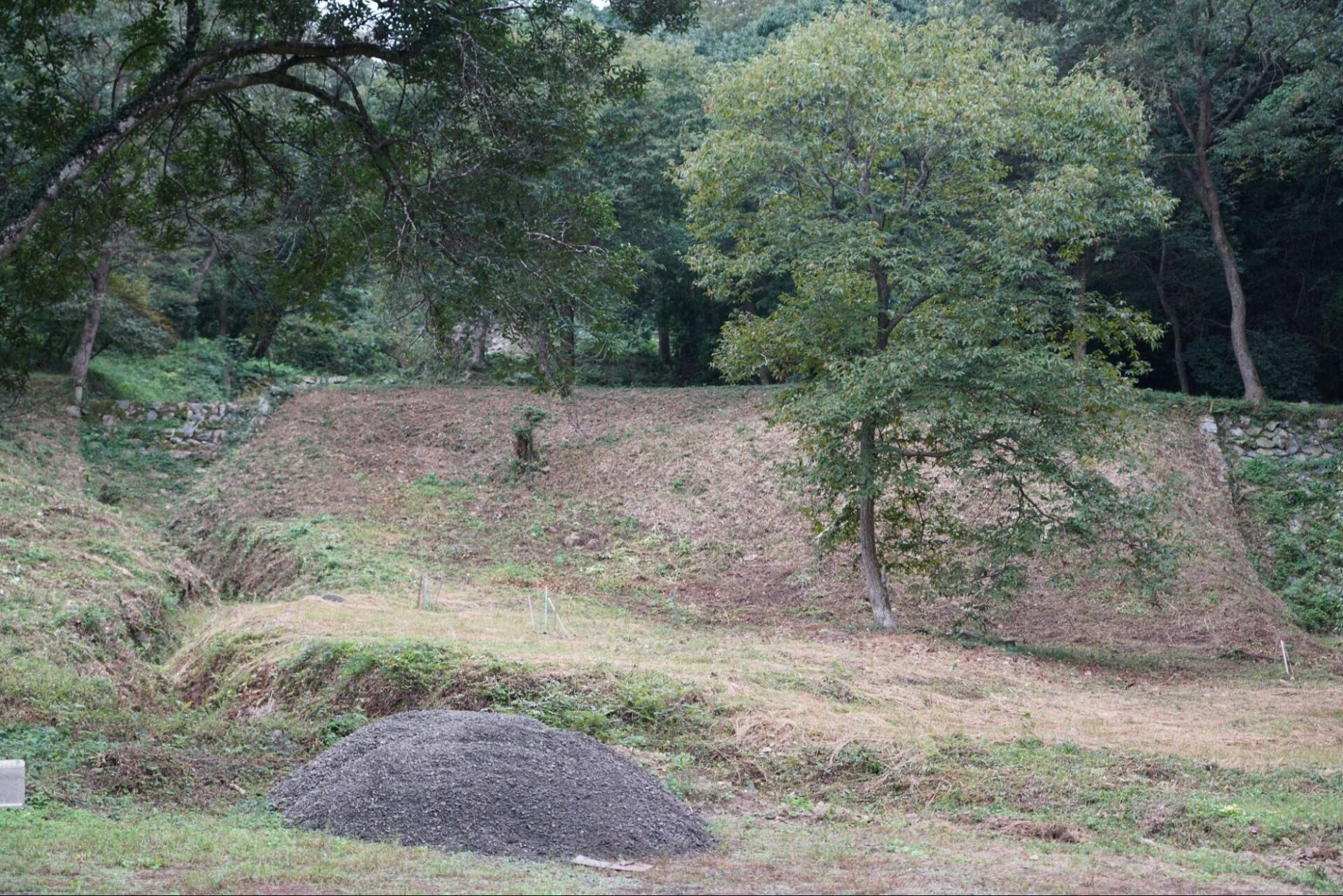 草刈り後の整備された別所砂留周辺の山林と堆積された砂利の山
