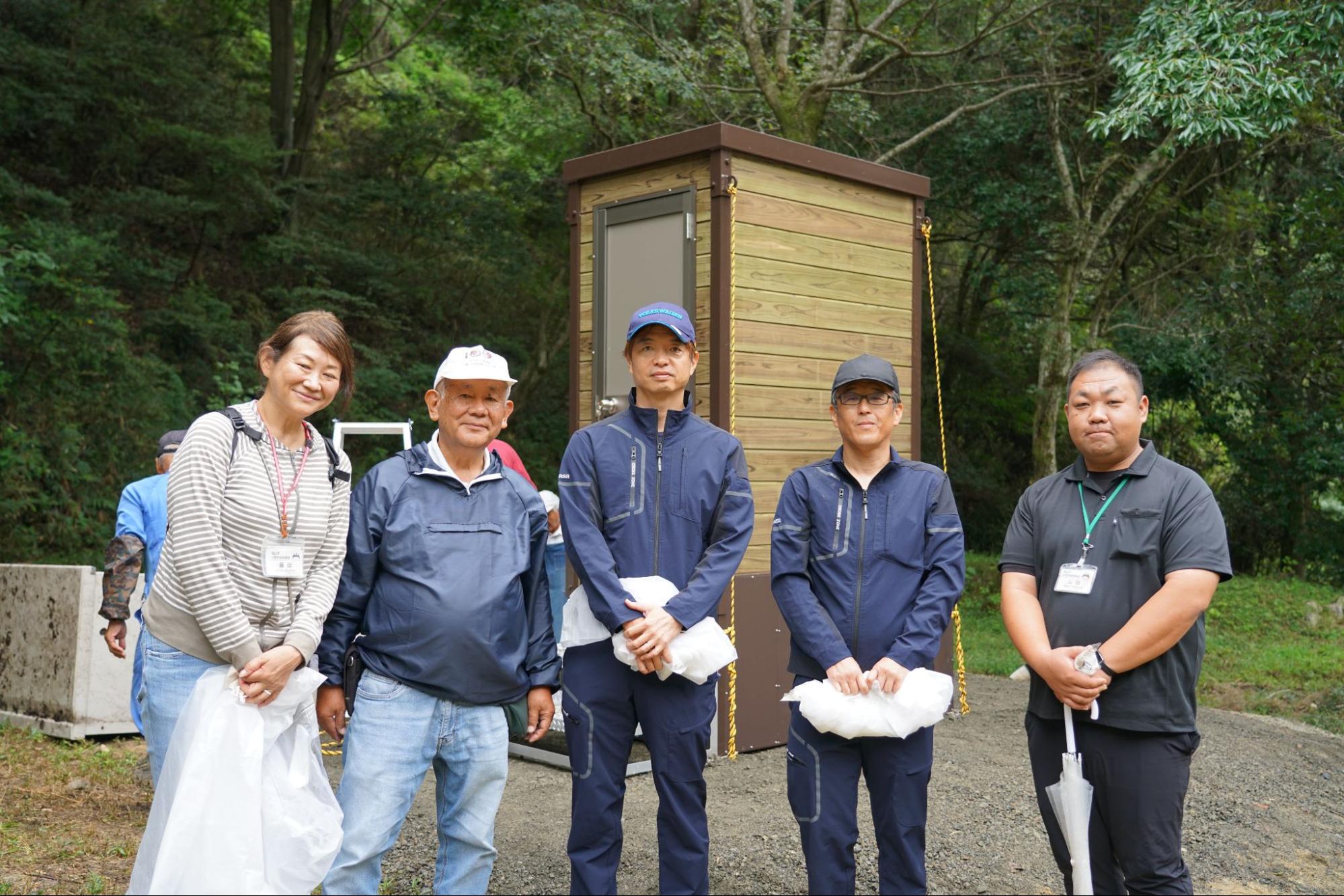 完成したバイオトイレの前で記念撮影をする市民団体・行政・企業関係者